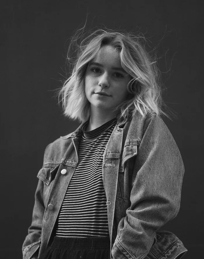 Black-and-white portrait of a young woman in a denim jacket.